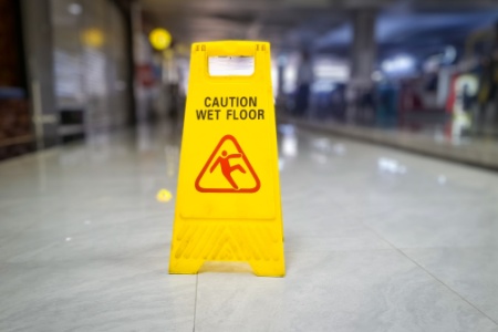 A "Caution Wet Floor" sign on a tiled floor, representing the concept of premises liability and the duty to warn of hazards.
