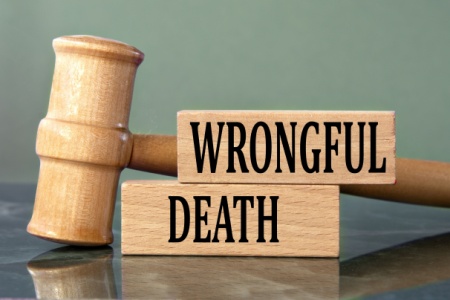 Wooden blocks spelling out "WRONGFUL DEATH" next to a judge's gavel.